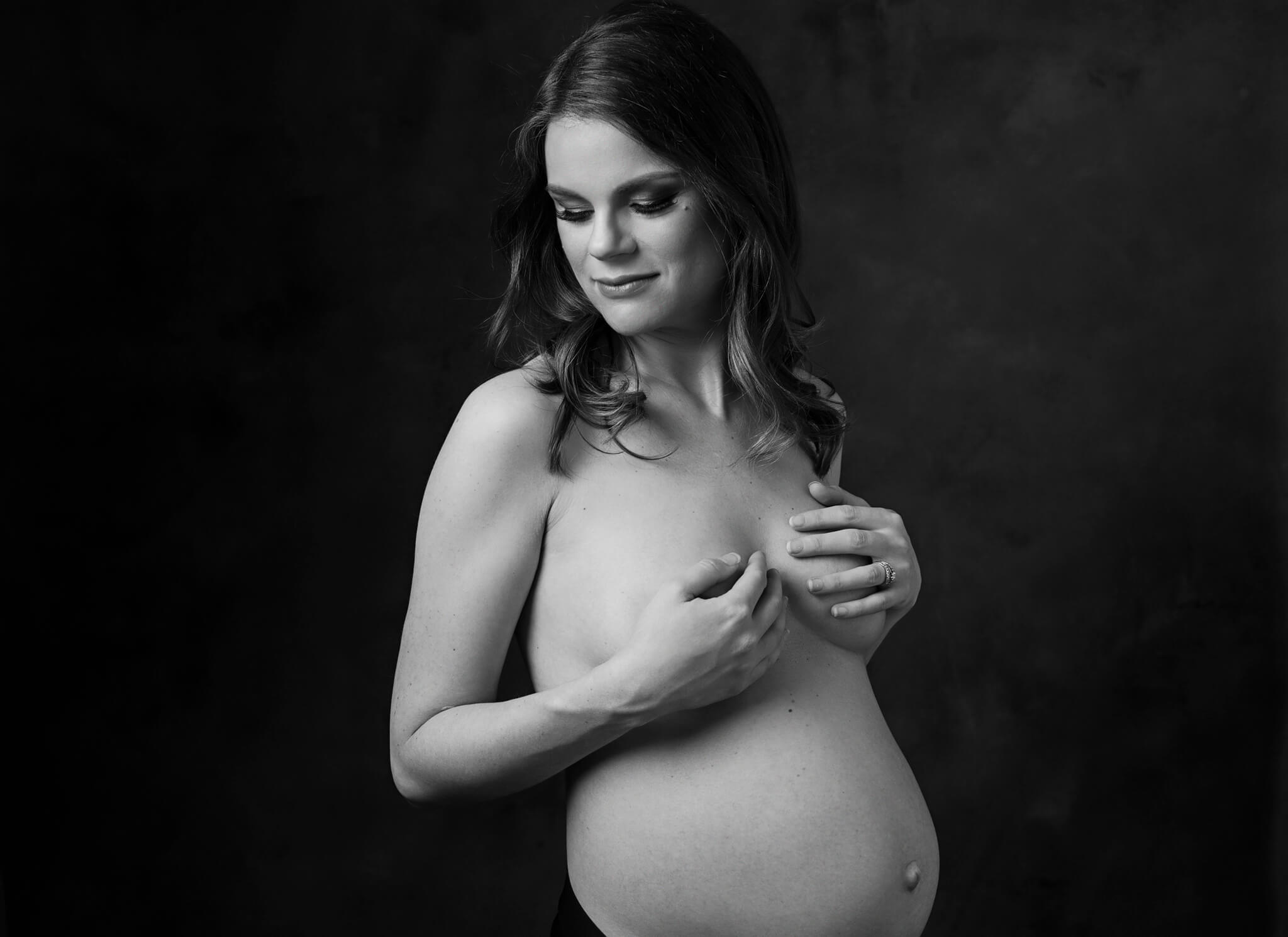 A mom to be stands in a studio with bump exposed