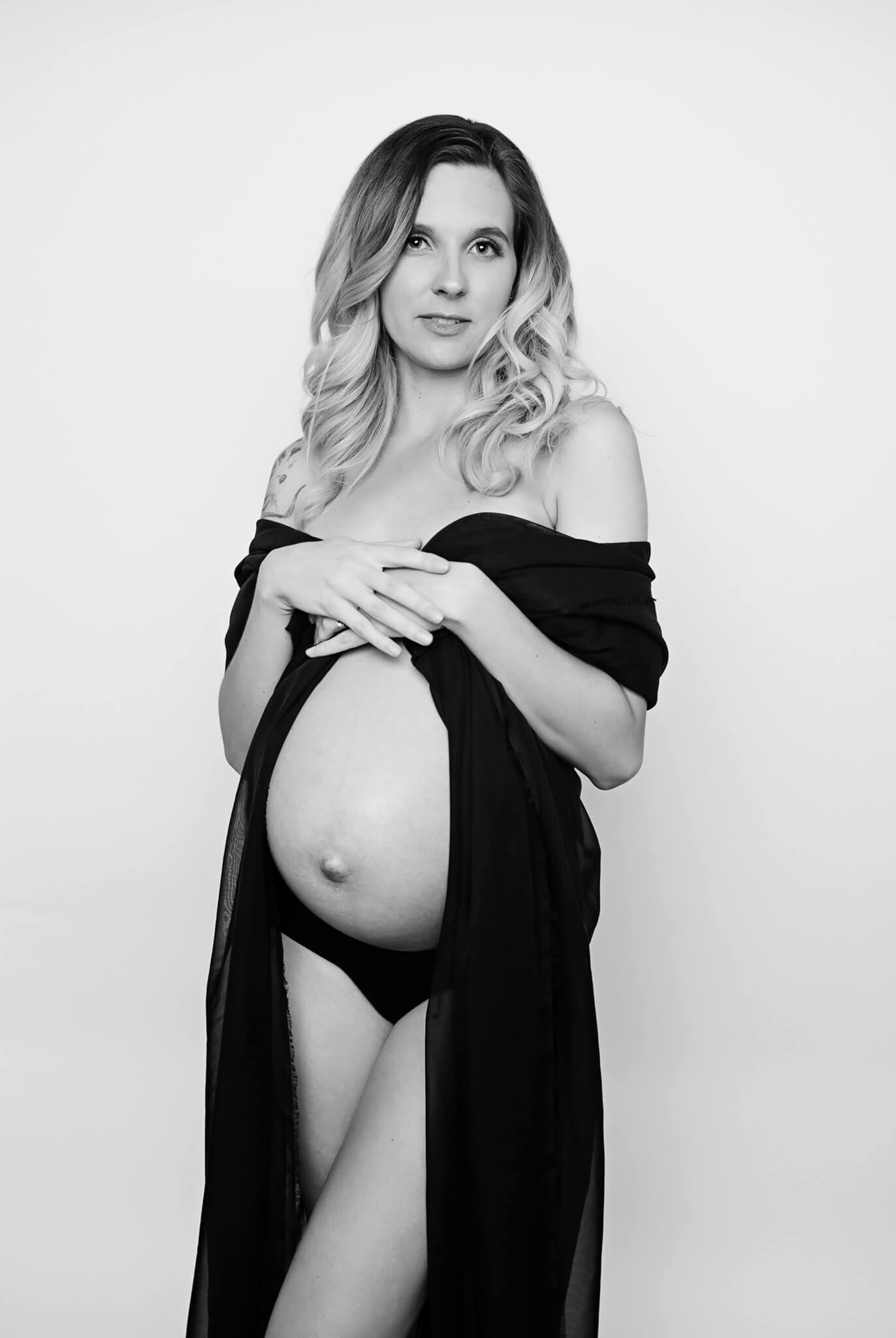 A pregnant woman covers with a black slip while standing in a studio with bump exposed after meeting austin doulas