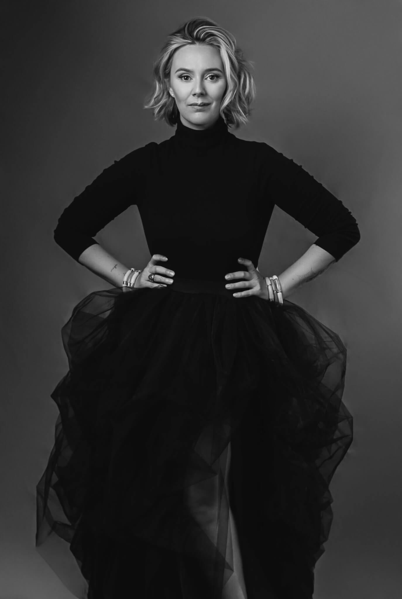 woman in her 40's is posing with a black tulle skirt and a turtleneck bodysuit in her glamour portrait