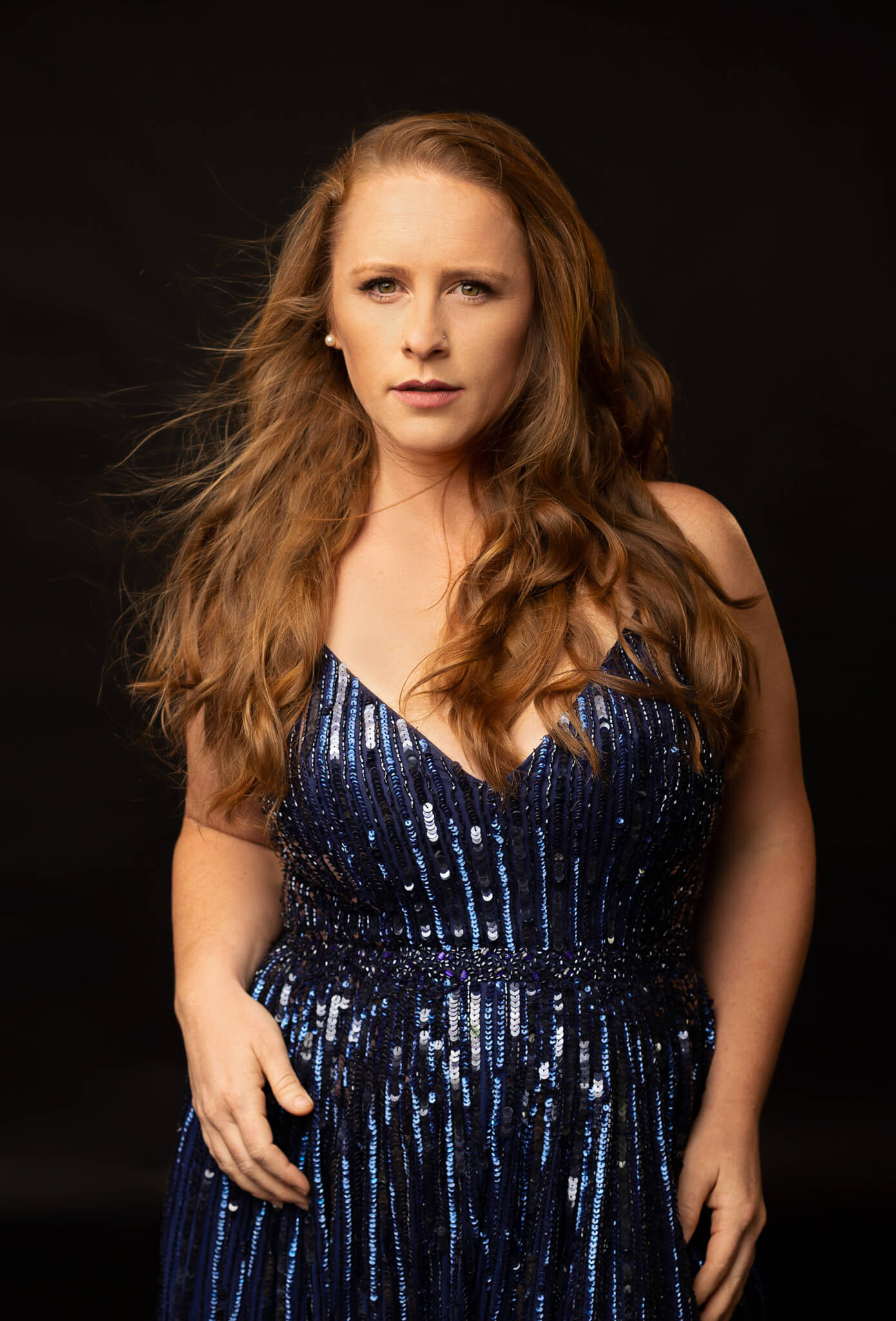 red hair woman is posing in a blue sequin dress for her glamour portrait in Austin Texas