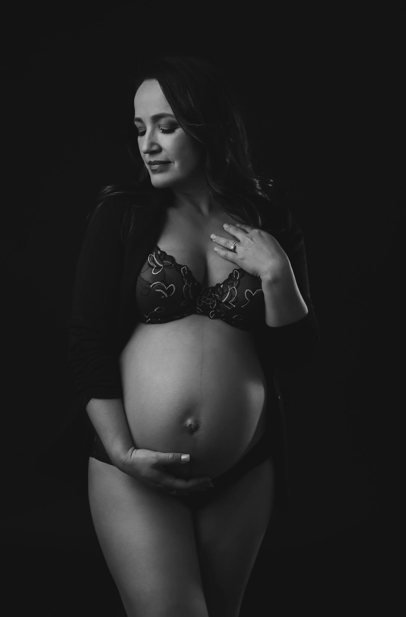 expectant mama is wearing lingerie and posing in a romantic way for a maternity photography session in black and white