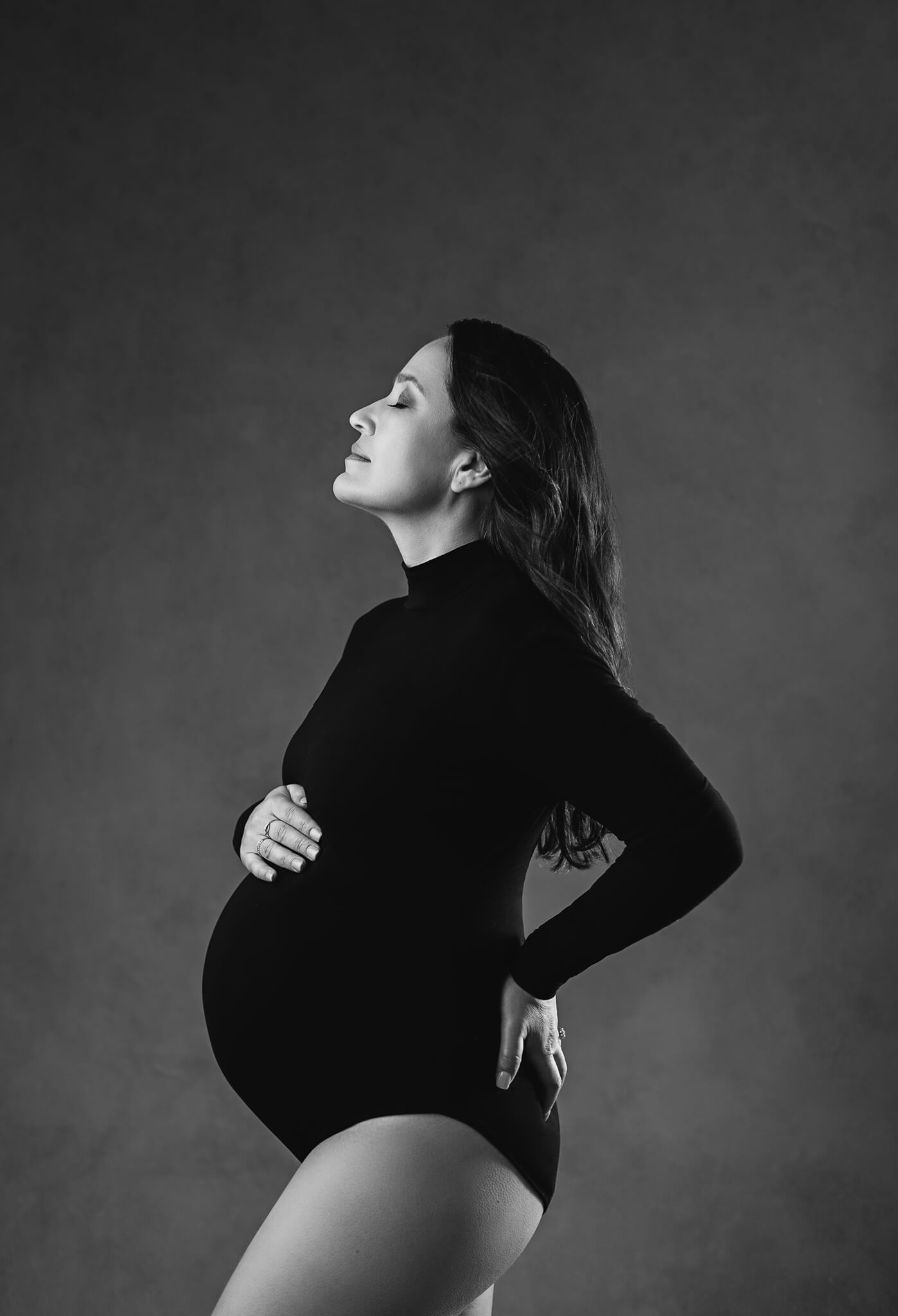 mature woman is wearing a black bodysuit while she poses for Austin maternity photographer 