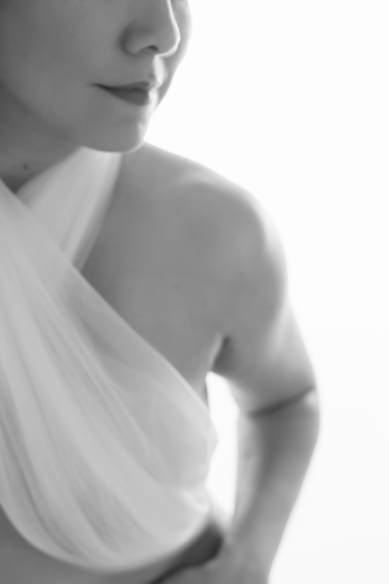 elegant boudoir image of a woman looking sideways and in a tight crop wearing white tulle