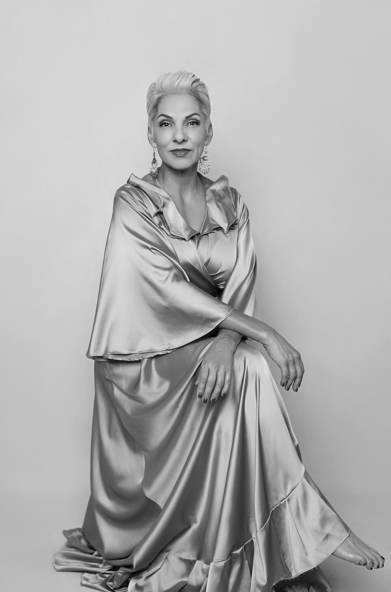 black and white portrait of a beautiful short hair woman, she is sitting and crossing her arms over her knees looking very relaxed