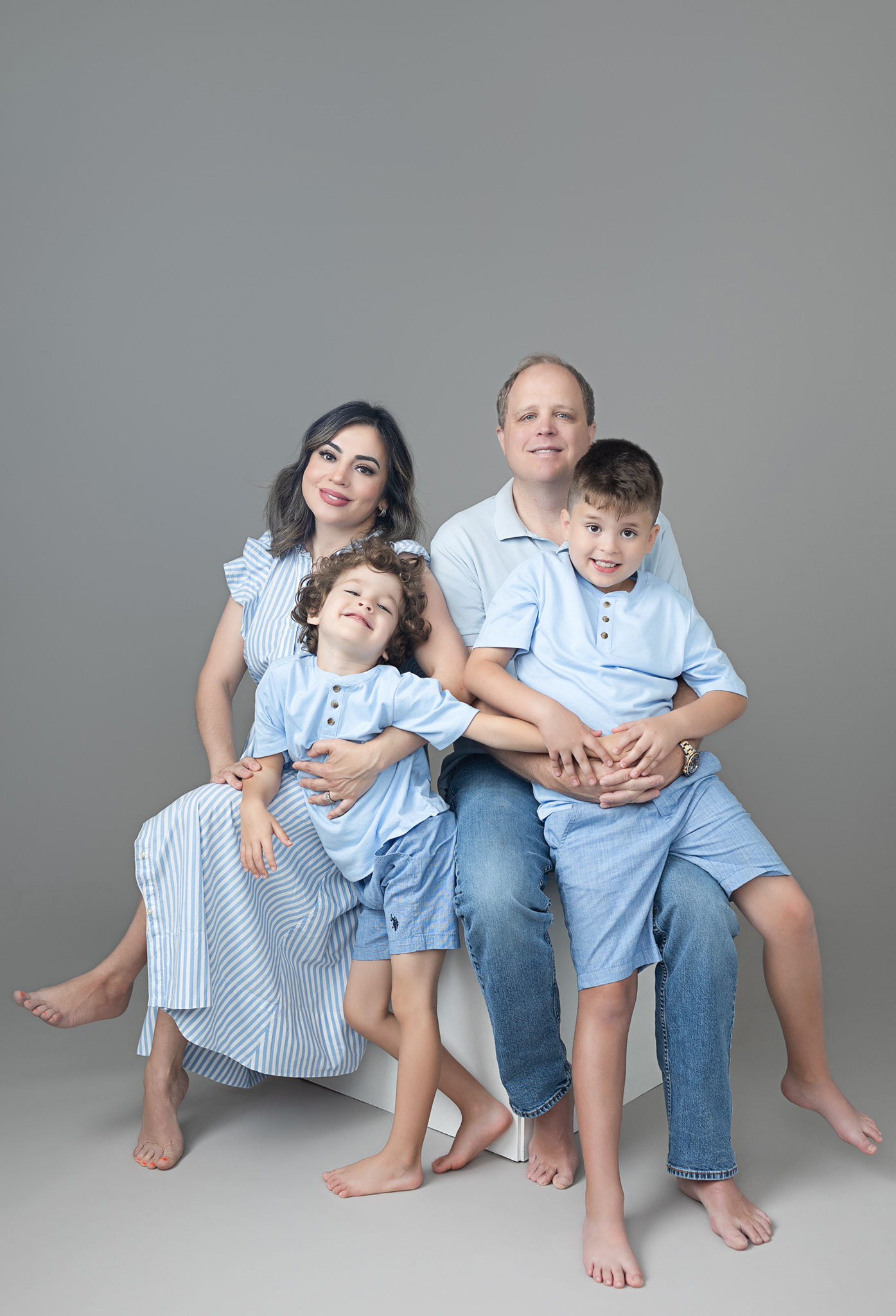 family portrait show a happy family wearing blue in a studio minimalistic setup