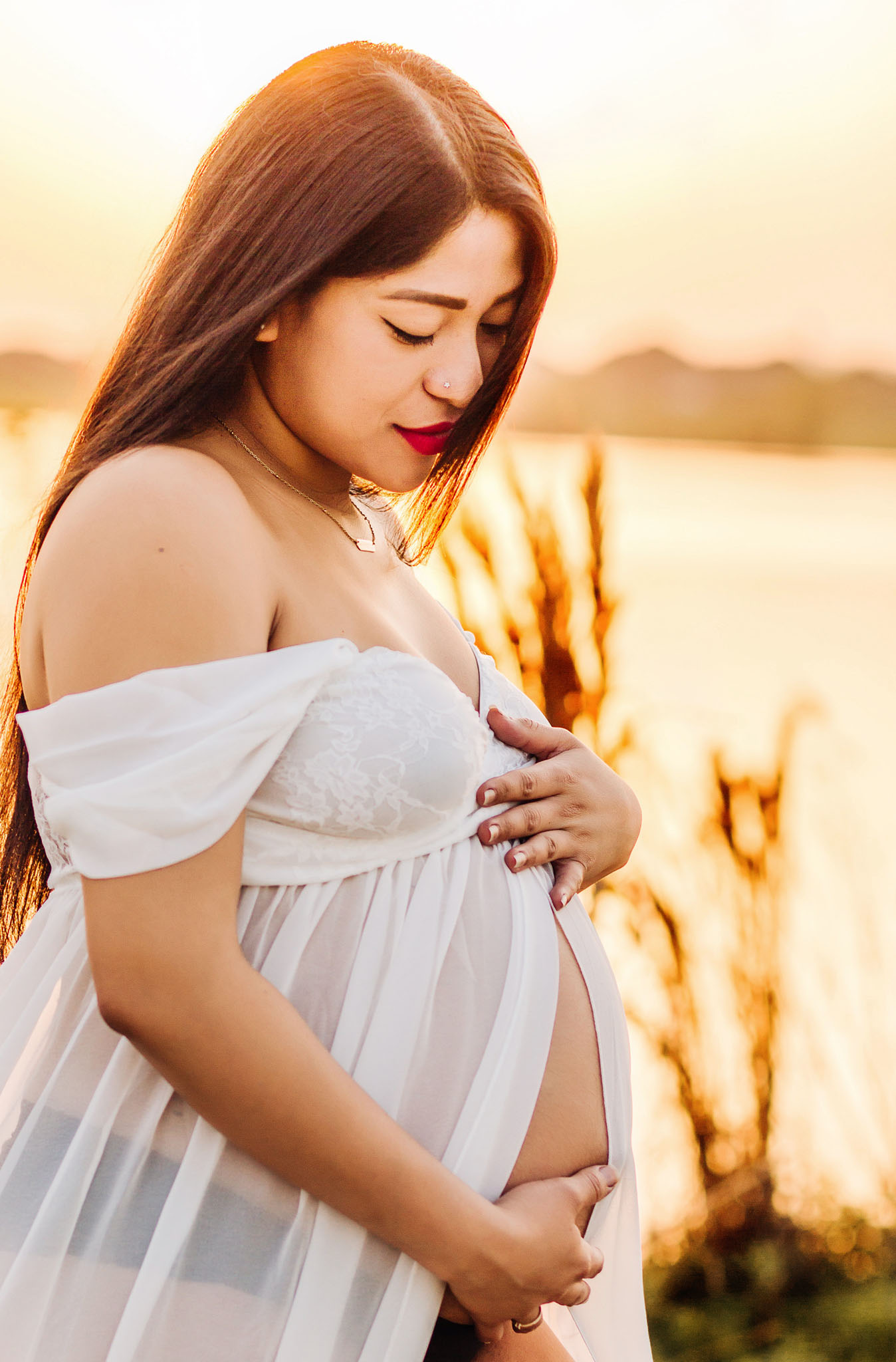 sunset photoshoot of a pregnant lady with water as a background