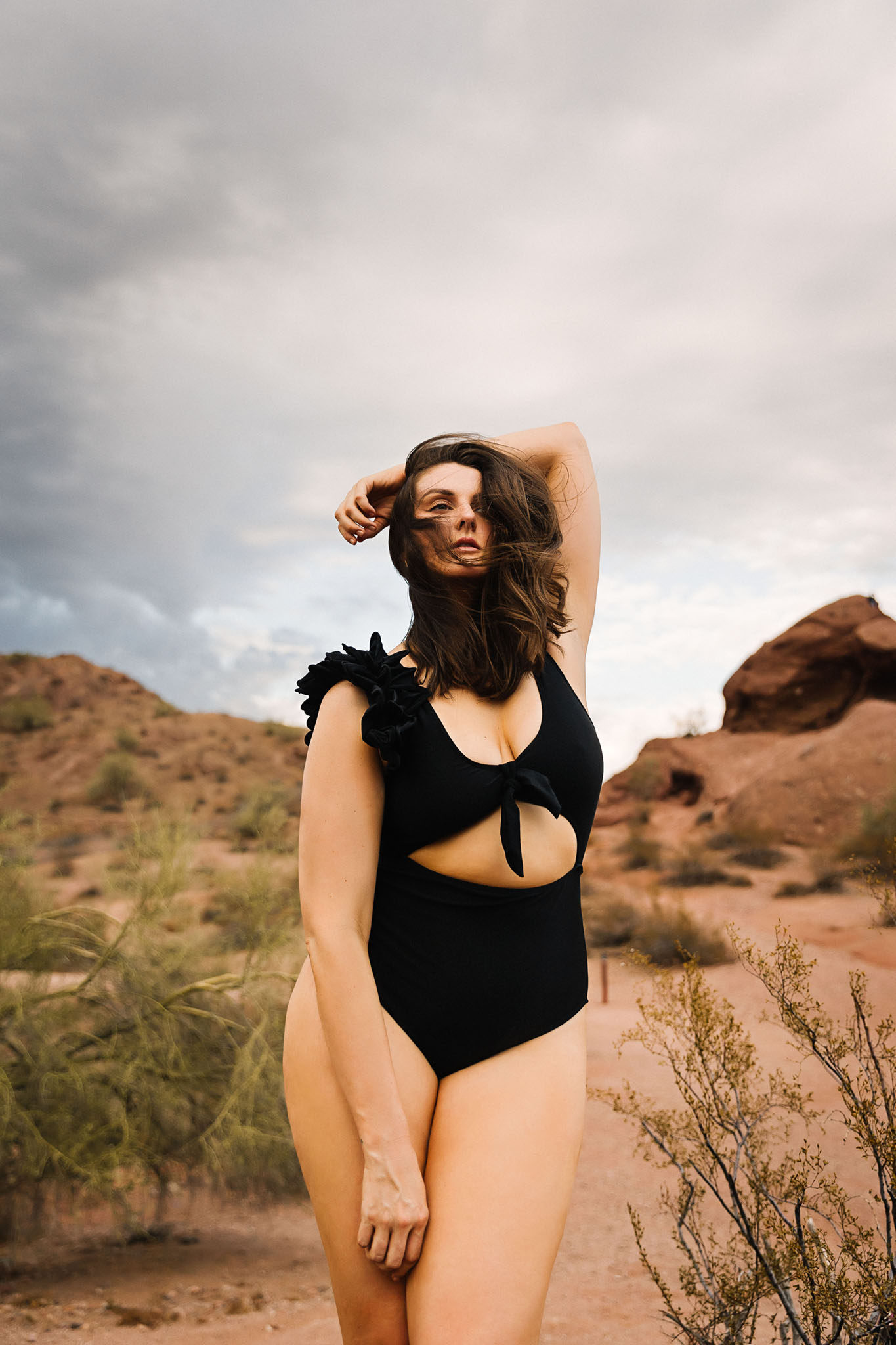 boudoir session in a natural park while the model is wearing a black bodysuit in a sexy pose