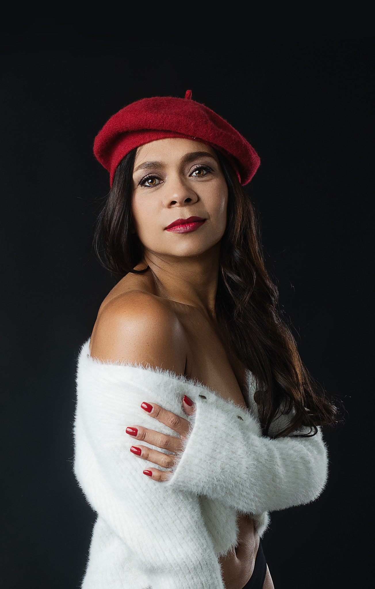 lady wearing a white sweater and a red hat over black backdrop in a studio in Austin, Texas