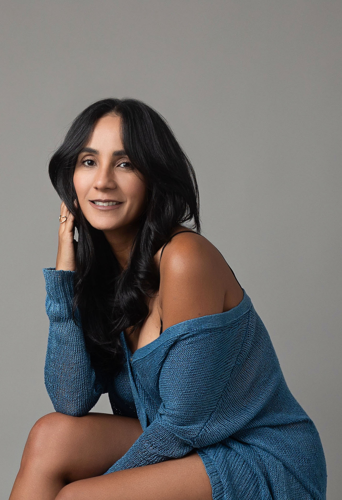 photographer takes self portrait to celebrate her birthday, wearing a blue top and grey background